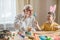 Happy elderly man granfather preparing for Easter with grandson. Portrait of smiling boy with bunny ears painted  colored eggs for