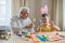 Happy elderly man granfather preparing for Easter with grandson. Portrait of smiling boy with bunny ears painted  colored eggs for