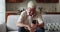 Happy elderly man sit at home hold smartphone make videocall