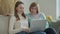 Happy elderly middle mother sitting on couch with her daughter, looking at laptop. Happy mature woman with her adult