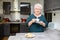 Happy elderly senior active woman drinking coffee in a modern kitchen at home