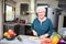 Happy elderly senior old active woman cooking at home in modern kitchen