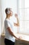 Happy elderly woman drinking water from plastic bottle after sport training, vertical