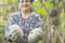 Happy elderly woman farmer holding pumpkins in hands at garden f