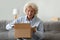Happy elderly woman open parcel shopping online