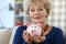 Happy elderly woman shows pink ceramic piggy bank