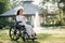 Happy elderly woman sitting on wheelchair outdoor in park relax your mind with green nature. Nursing home hospital garden concept