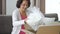 Happy elderly woman unpack box with vase sitting at sofa in apartment.