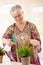 Happy elderly woman watering plant