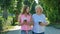 Happy elderly woman and young woman walking park lane drinking coffee. Adult Mother and Daughter walking in the park