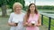 Happy elderly woman and young woman walks along the waterfront and drinking coffee. Adult Mother and Daughter walking in the park.