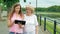 Happy elderly woman and young woman walks along the waterfront and tablet computer. River in the background.