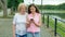 Happy elderly woman and young woman walks along the waterfront and using smartphone. Adult Mother and Daughter walking in the park