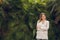 Happy elegant businesswoman standing near lush exotic plants and smiling