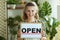 Happy elegant small business owner woman showing welcome sign