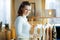 Happy elegant woman choosing sweaters hanging on clothes rack