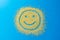 Happy emoji smile on a blue background. Smiley from yellow sugar grains. Stock image.
