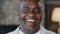 Happy emotional african american adult man sincere smiling laughing loud indoors head shot of mature senior pensioner