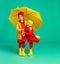 happy emotional cheerful children friends laughing  with yellow umbrella   on colored green background