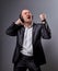 Happy emotional dancing and singing bald man listening the music in wireless headphone on dark grey background. Closeup