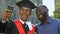 Happy emotional teenager in magisterial gown and father making selfie graduation