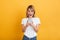 Happy emotional young blonde woman posing isolated over yellow wall background dressed in white casual t-shirt using mobile phone