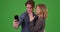 Happy engaged couple taking picture with cell phone on green screen