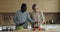Happy engaged multiethnic couple preparing dinner in kitchen together