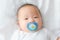 Happy and enjoy Portrait of a newborn Asian baby boy on the bed ,a dummy in his mouth, Charming