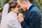 Happy enloved newlywed pair, tender bride and gentle groom, holding hands together while walking in green park