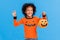 Happy ethnic boy in pumpkin costume scary gestures and celebrates Halloween and laughs on a bright blue background