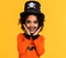 Happy ethnic boy in pumpkin costume and terrible makeup celebrates Halloween and laughs on yellow background