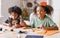 Happy ethnic children girl and boy making Halloween home decorations together