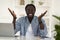 Happy Excited Black Man Sitting At Desk And Spreading Hands At Camera