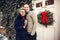 Happy excited caucasian couple standing together and hug outdoors at Christmas time near the decorated house at winter time