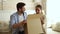 Happy excited couple customers open cardboard box sitting on sofa