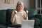 Happy excited grey haired woman celebrating online win, using laptop