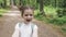 Happy, excited laughing small girl makes video selfie at smartphone camera and spins around during walk in summer park