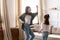 Happy excited mother and daughter dancing in modern living room