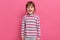 Happy excited preschooler girl wearing casual style striped shirt posing isolated over pink background with satisfied and