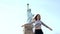 Happy excited smiling European tourist woman raises arms at Statue of Liberty in New York on summer day slow motion.