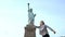 Happy excited successful Caucasian female student jumping with joy at Statue of Liberty monument in USA slow motion.