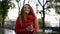 Happy, excited woman in red coat walking with a takeaway drink in the street in a rainy autumn. Gorgeous young girl with