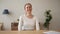 Happy excited woman sitting at desk chatting looking at webcam