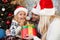 Happy exited girl in Santa`s hat looking at Chrismas gift, while