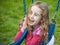 Happy face on a little girl playing with swings