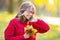 Happy fall girl smiling and joyful holding autumn leaves. Beautiful young girl with maple leaves in red cardigan