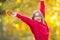 Happy fall girl smiling and joyful holding autumn leaves. Beautiful young girl with maple leaves in red cardigan