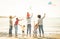 Happy families group with parents and children playing with kite at beach
