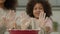 Happy family African American ethnic mom and little daughter enjoy cooking together showing messy dirt hands palms dust